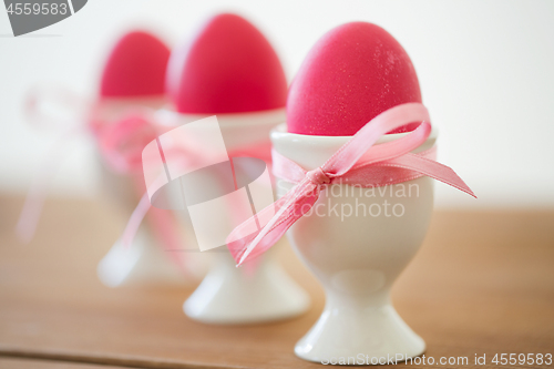 Image of pink colored easter eggs in holders on table