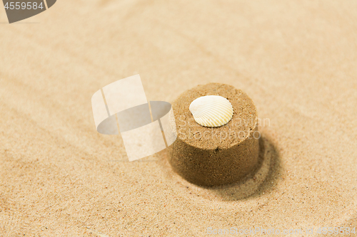 Image of sand shape made by mold with shell on summer beach