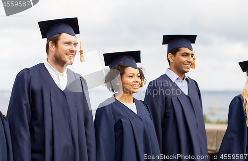 Image of happy students or bachelors in mortar boards