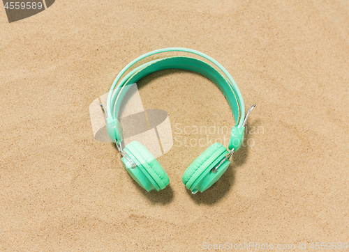Image of earphones on summer beach sand