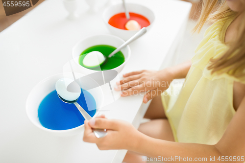 Image of girl coloring easter eggs by liquid dye at home