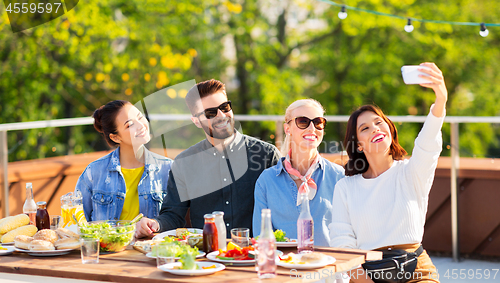 Image of happy friends taking selfie at rooftop party