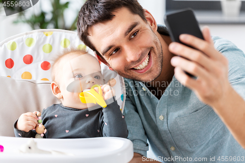 Image of father with baby daughter taking selfie at home