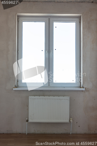 Image of View of the window and the battery under the window in the interior of an unrepaired room