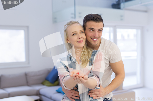 Image of couple showing small red house in hands