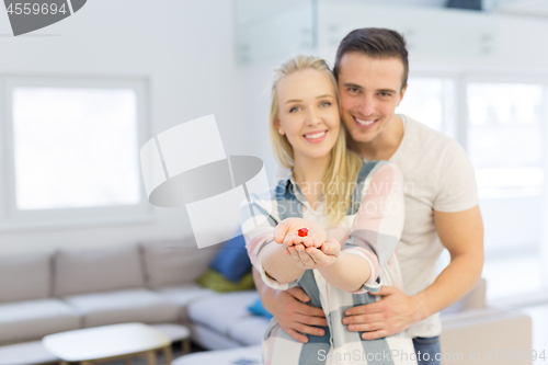 Image of couple showing small red house in hands