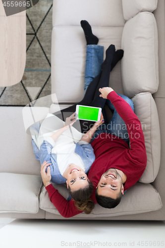 Image of couple relaxing at  home with tablet computers