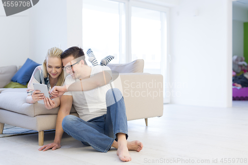 Image of couple relaxing at  home with tablet computers