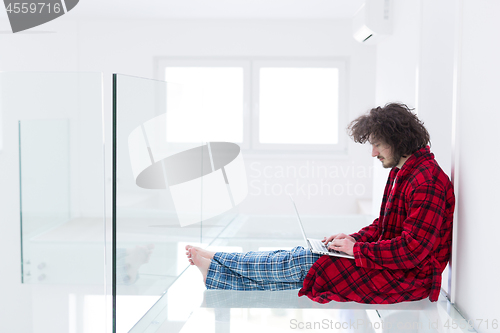 Image of young freelancer in bathrobe working from home