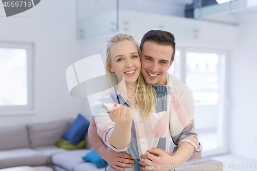 Image of couple showing small red house in hands