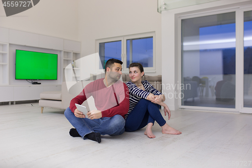 Image of Young Couple using digital tablet on the floor