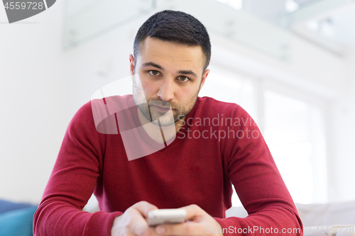 Image of young man using a mobile phone  at home