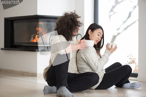 Image of happy multiethnic couple  in front of fireplace