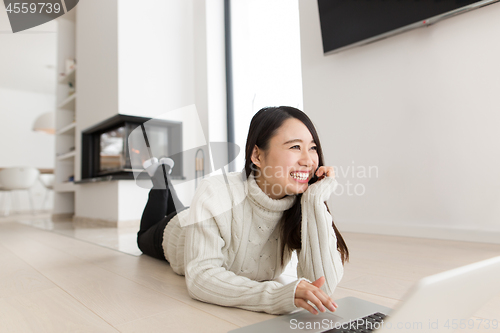 Image of young Asian woman using laptop on the floor