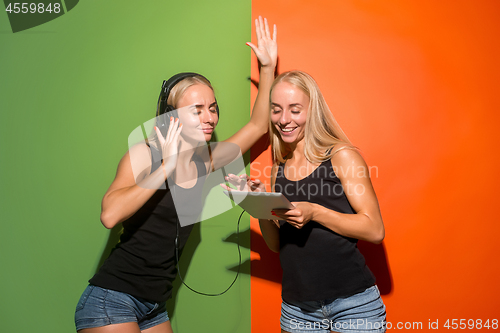 Image of Picture of two young happy women looking at the camera and holding laptop.