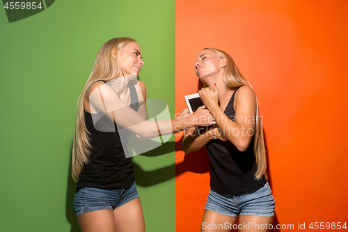 Image of Picture of two young happy women looking at the camera and holding laptop.