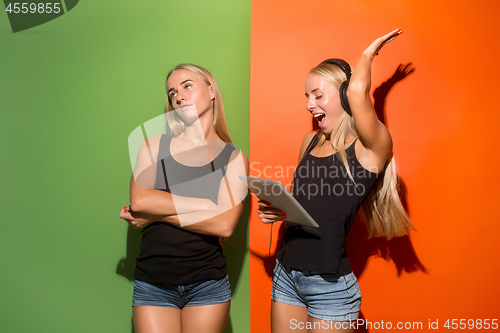 Image of Picture of two young happy women looking at the camera and holding laptop.