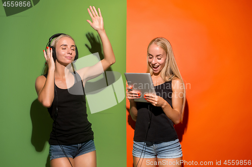 Image of Picture of two young happy women looking at the camera and holding laptop.