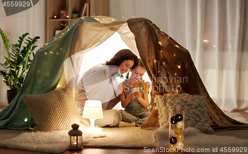 Image of happy family with smartphone in kids tent at home