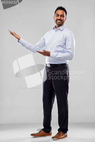 Image of indian businessman holding something over grey