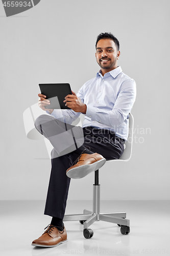 Image of indian businessman with tablet pc on office chair