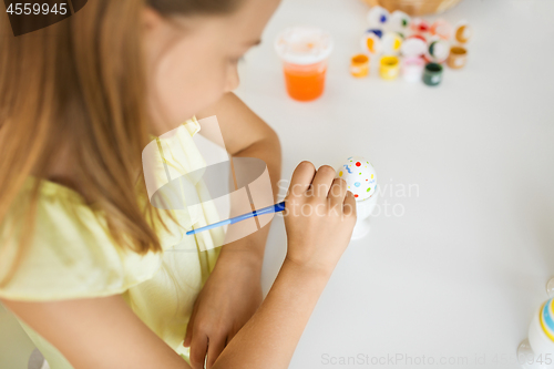 Image of close up of girl coloring easter egg by paintbrush