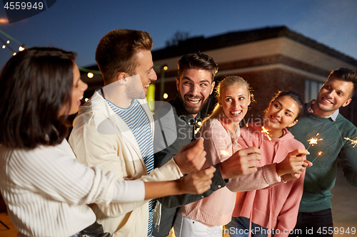 Image of happy friends with sparklers at rooftop party
