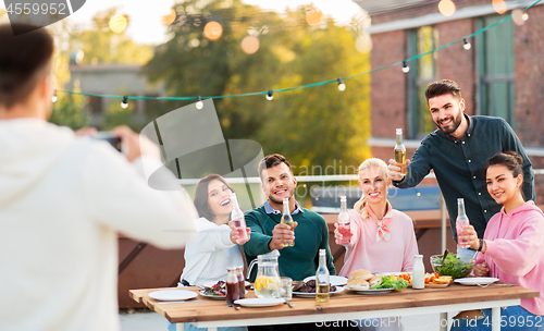 Image of happy friends photographing at rooftop party