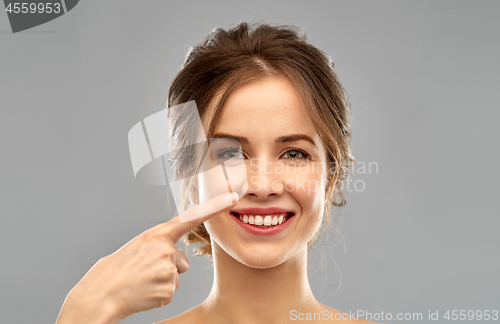 Image of beautiful young woman pointing to her nose