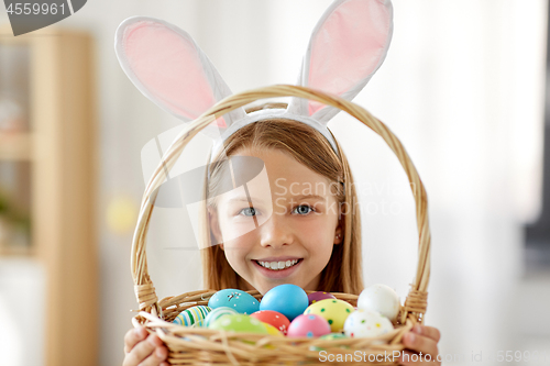 Image of happy girl with colored easter eggs at home