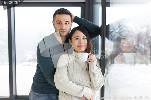 Image of multiethnic couple enjoying morning coffee by the window