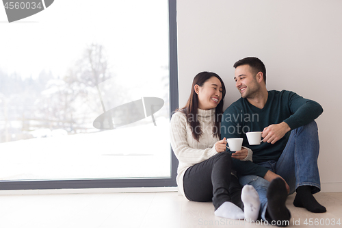 Image of multiethnic couple enjoying morning coffee by the window