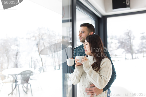 Image of multiethnic couple enjoying morning coffee by the window