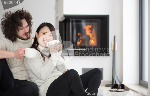 Image of happy multiethnic couple  in front of fireplace