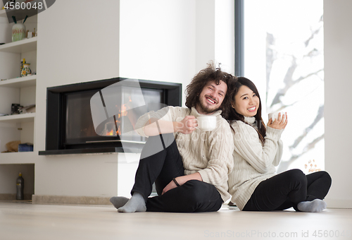 Image of happy multiethnic couple  in front of fireplace