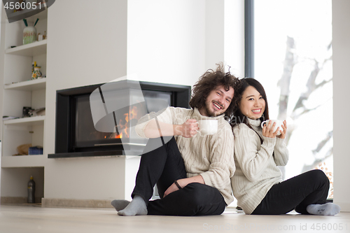 Image of happy multiethnic couple  in front of fireplace