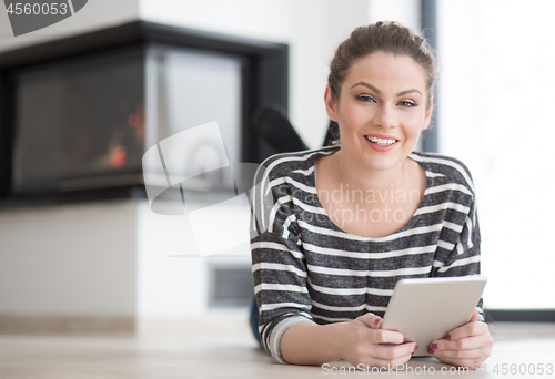 Image of woman using tablet computer in front of fireplace