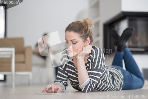 Image of woman using tablet computer in front of fireplace