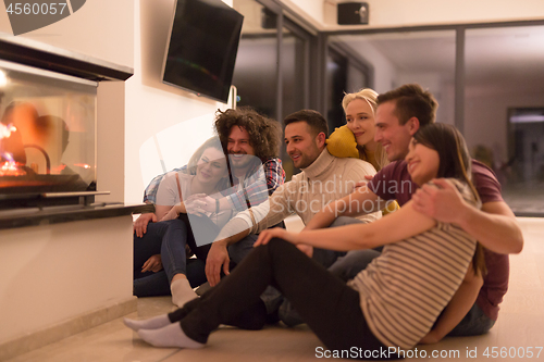 Image of multiethnic couples sitting in front of fireplace