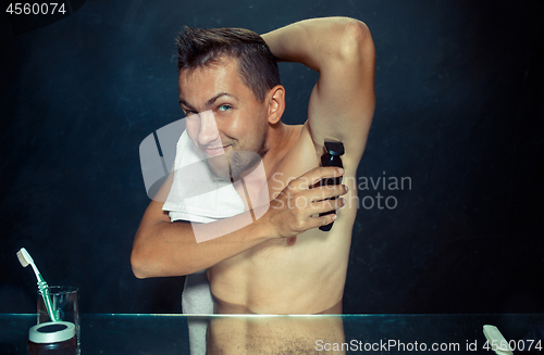 Image of Photo of handsome man shaving his armpit