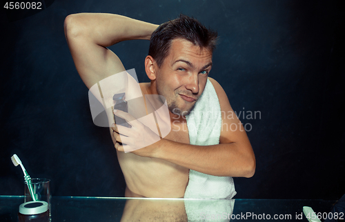 Image of Photo of handsome man shaving his armpit