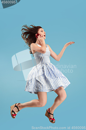 Image of Full length of pretty young woman with mobile phone while jumping