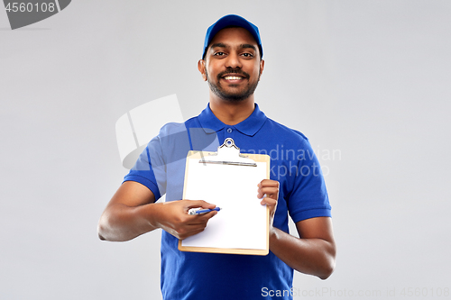 Image of happy indian delivery man with clipboard in blue