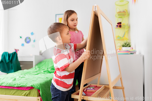 Image of happy kids drawing on easel or flip board at home
