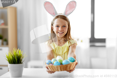 Image of happy girl with colored easter eggs at home