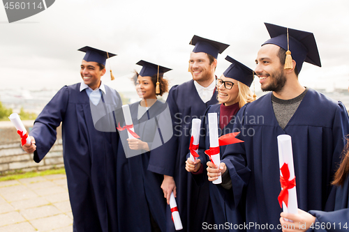 Image of happy students in mortar boards with diplomas