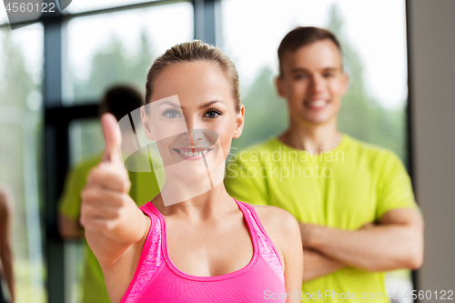 Image of smiling man and woman showing thumbs up in gym