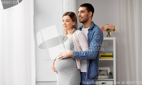 Image of man hugging pregnant woman at window at home