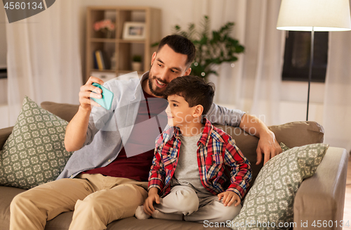 Image of father and son taking selfie at home