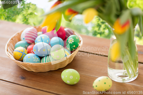 Image of colored easter eggs in basket and flowers